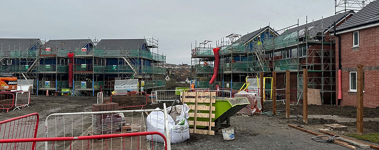 Scaffolded residential blocks during construction works, with site delivery and waste management in progress
