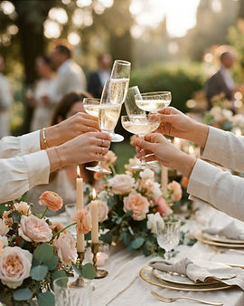 Hands raising champagne glasses in a toast over a candlelit table with blush garden flowers