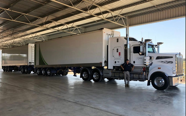 Kenworth prime mover with two trailers parked inside the depot shed