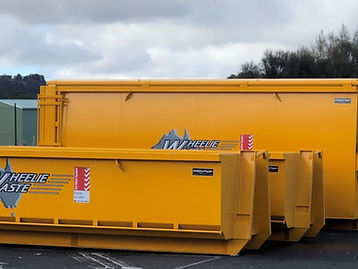 Three yellow Wheelie Waste skip bins lined up on asphalt