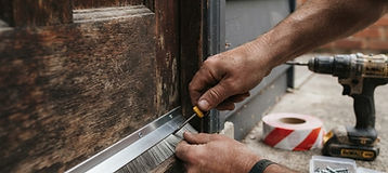 Stainless steel brush strip being fitted to the base of a timber exterior door