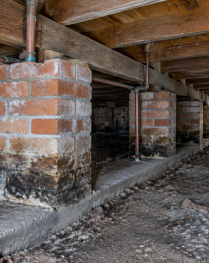 Brick piers and timber bearers inside the subfloor of an older house