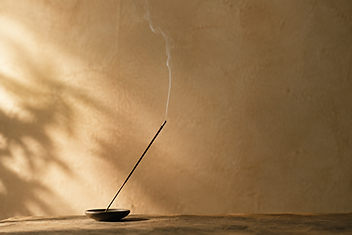 Incense smoke rising against a quiet wall