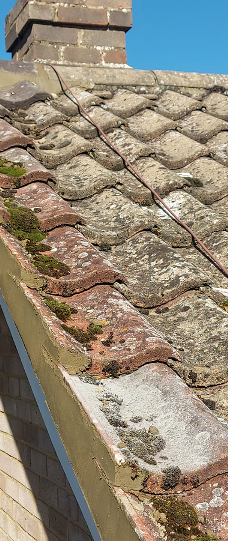 Concrete roof tiles and weathered mortar along a verge, seen from the scaffolding
