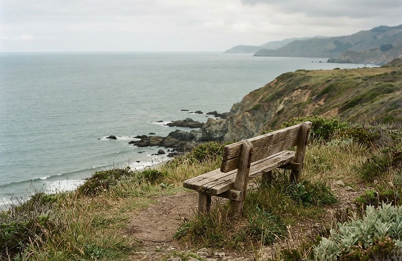 A weathered bench on a bluff above the sea