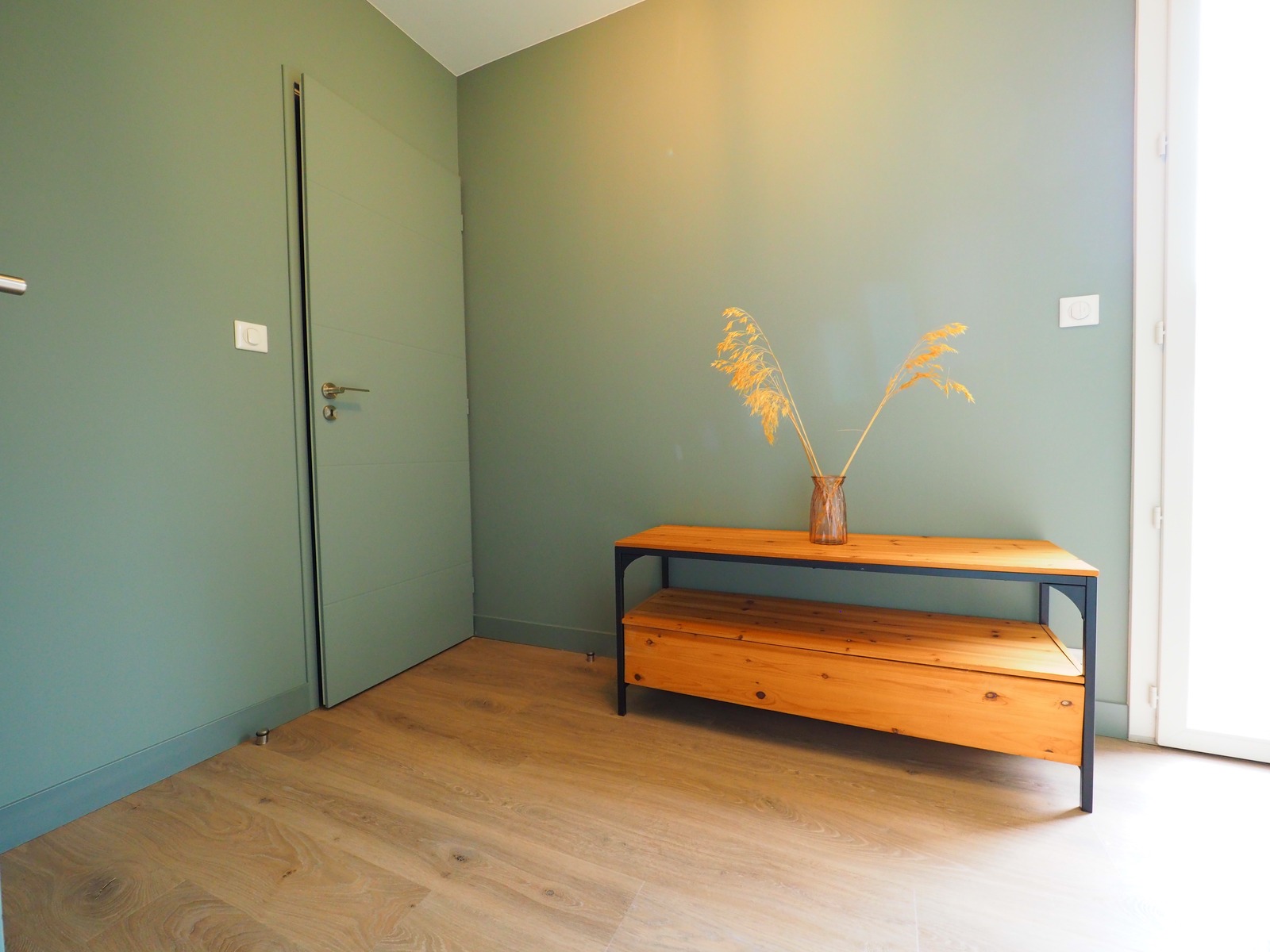 Association de bois et de peinture vert sauge dans une entrée