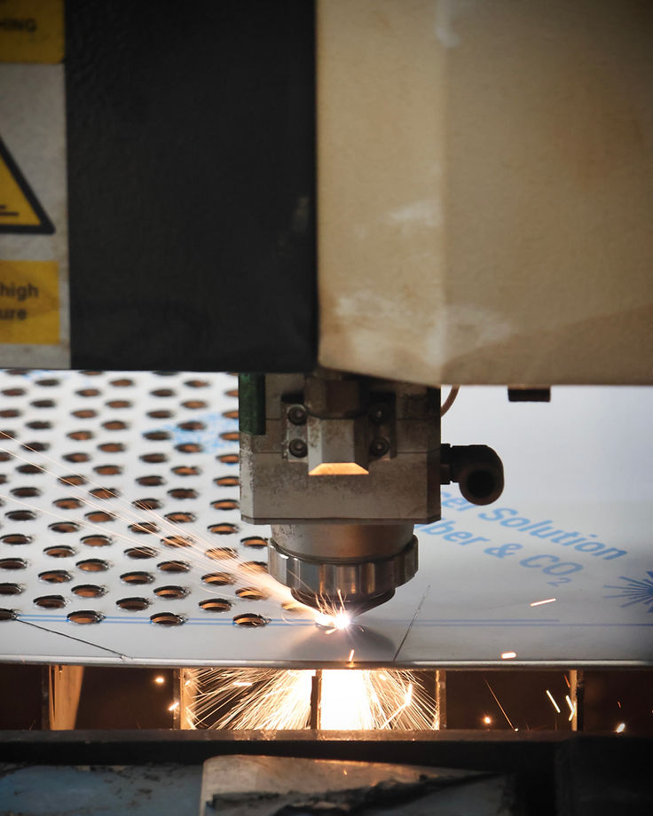 Cabezal de corte láser CNC cortando placa de acero con chispas en el taller