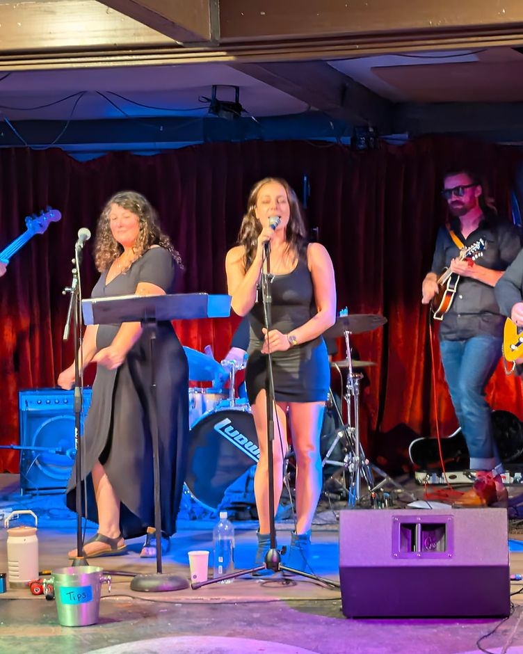 Special Lady Friend playing live in front of red velvet curtains under blue stage lights