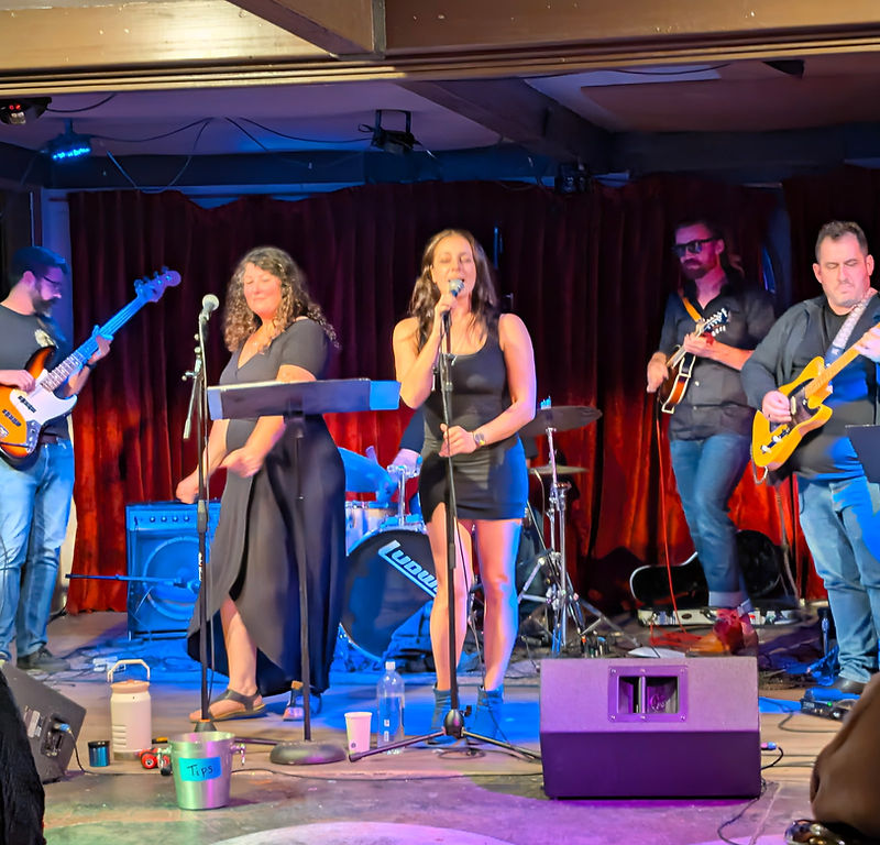 Special Lady Friend playing live as a five-piece in front of deep red velvet curtains, seen from the audience