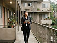 A property management professional walking an apartment breezeway with a tablet