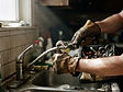 A maintenance technician repairing a kitchen faucet