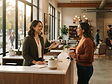 A community manager talking with a resident across a leasing office counter