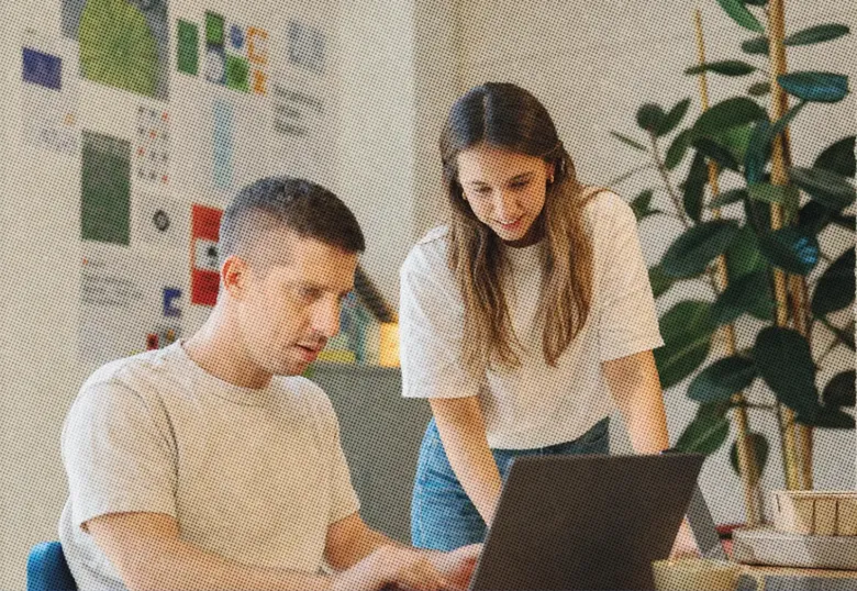 Two employees collaborating on a laptop