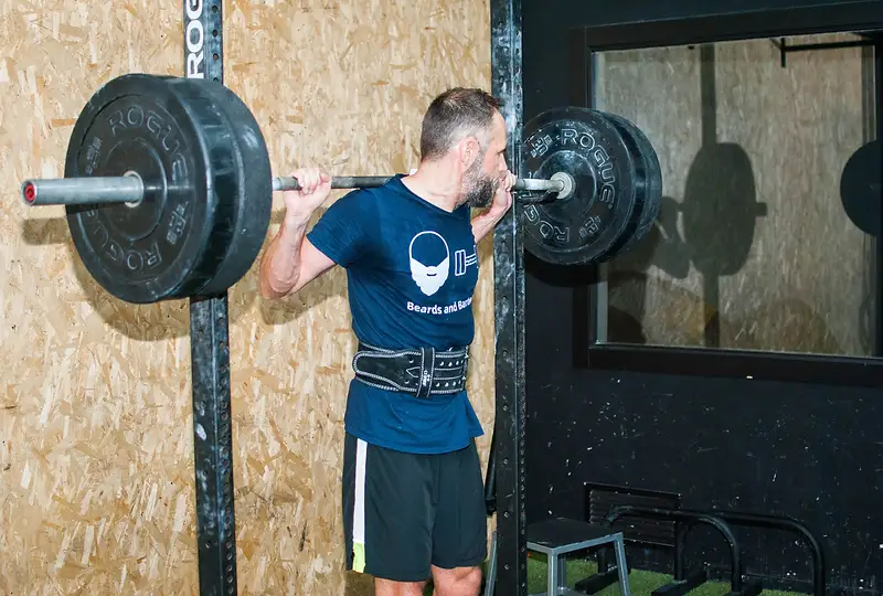 Athlete performing a barbell back squat in a power rack