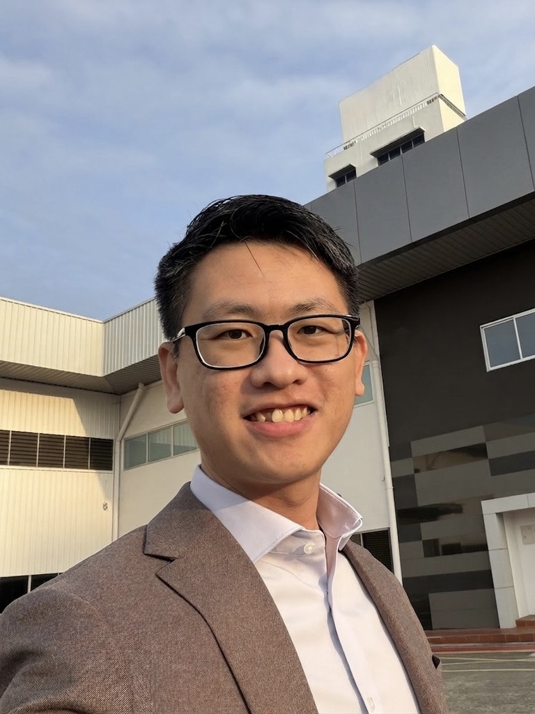 Junhan Chin outdoors wearing a blazer, smiling warmly