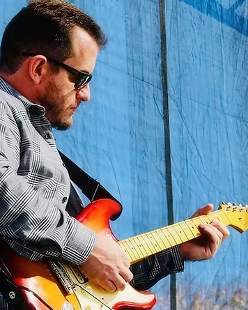 Julian Hoover playing a sunburst electric guitar against a blue backdrop