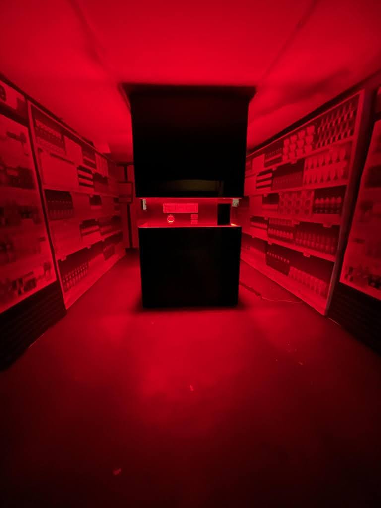 MSCHF custom experiential machine surrounded by illuminated red vending walls in a darkened room
