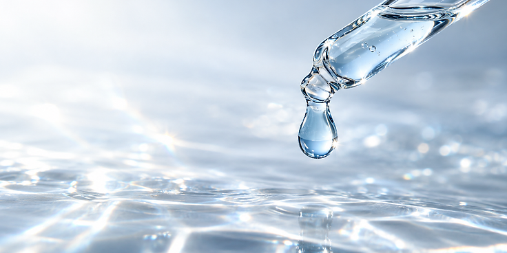 A glass dropper dispensing a single icy-blue droplet of serum above a reflective surface