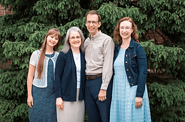 The Harmons' official prayer card photo — the family among evergreens