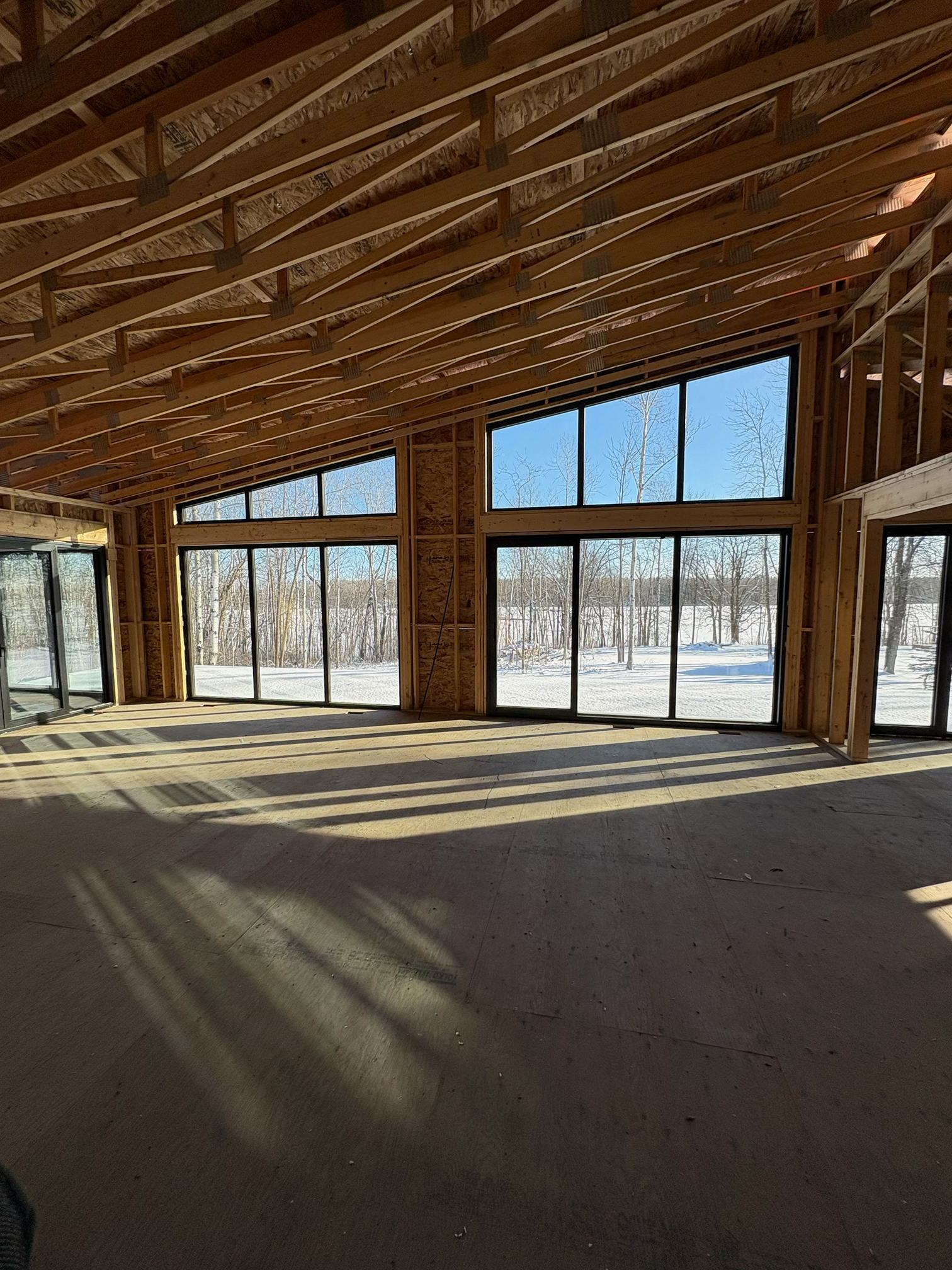 Framing phase of a residential glass installation showing window and door openings