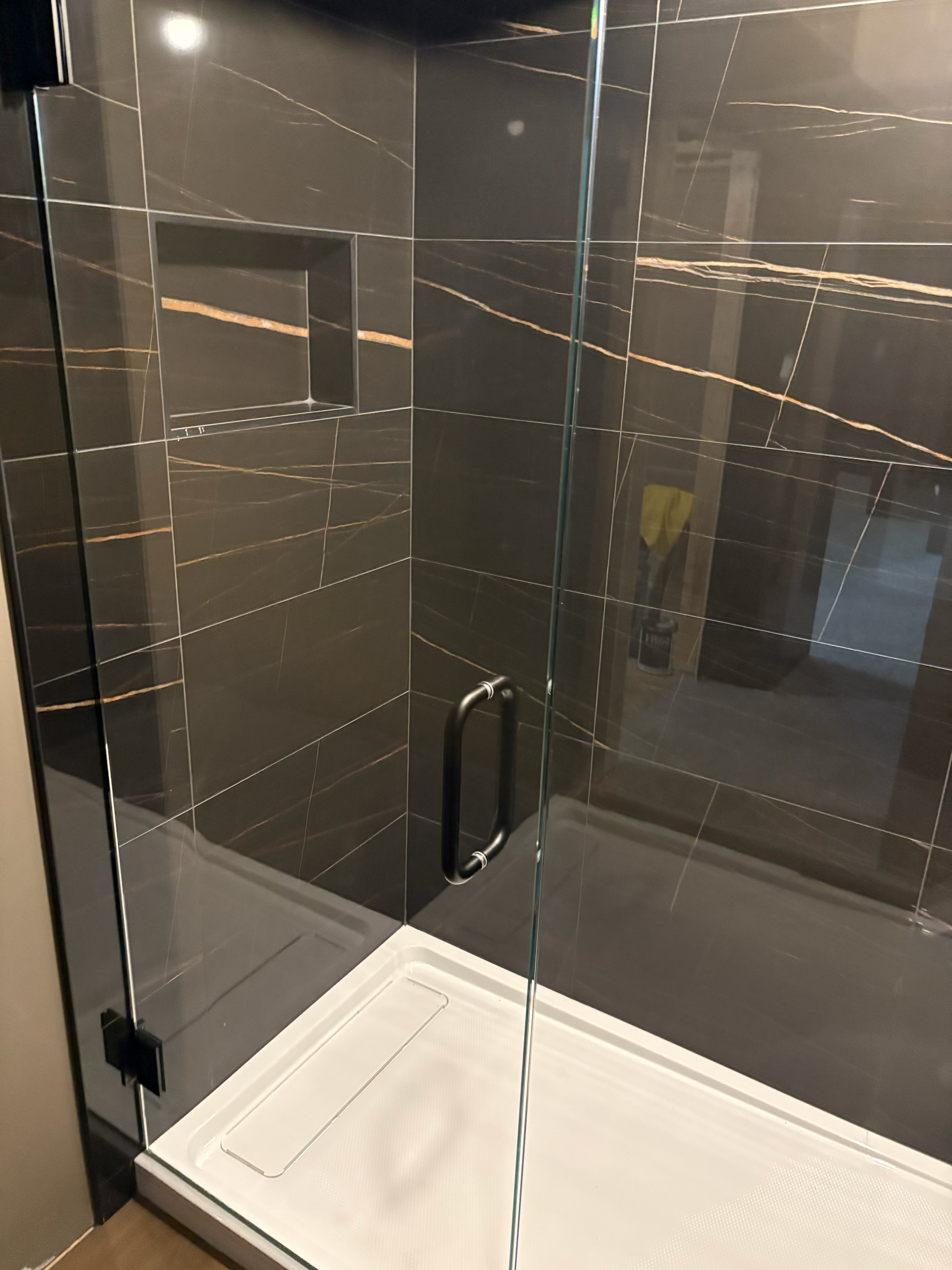 Frameless glass shower with built-in tile niche and matte black pull handle