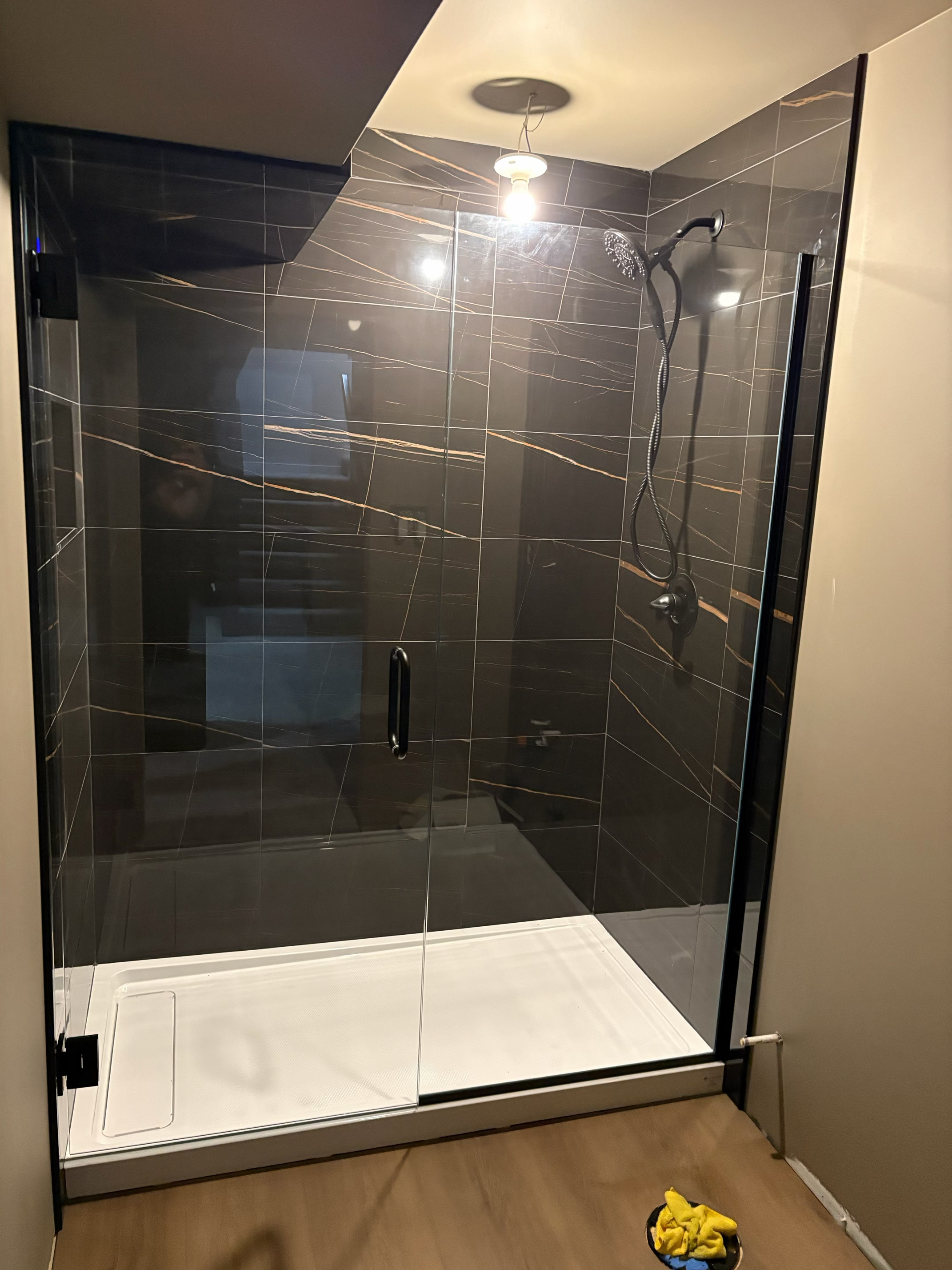 Custom frameless glass shower enclosure with matte black hardware in a modern Winnipeg bathroom
