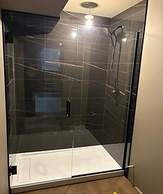 Custom frameless glass shower enclosure with matte black hardware in a modern Winnipeg bathroom