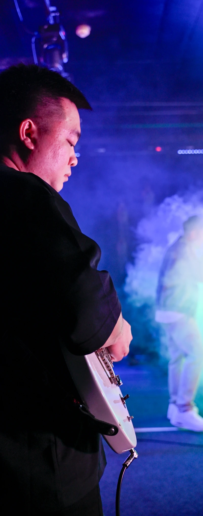 A guitarist waiting side-stage in blue light