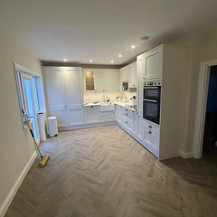 White shaker kitchen with Belfast sink and herringbone flooring in a Sussex home