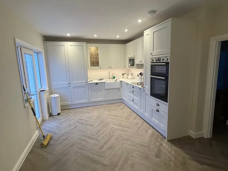 White shaker kitchen with Belfast sink and herringbone flooring in a Sussex home