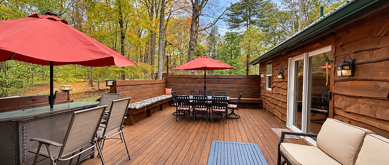 Back deck dining area with red umbrellas at Pocono Dream Cottage