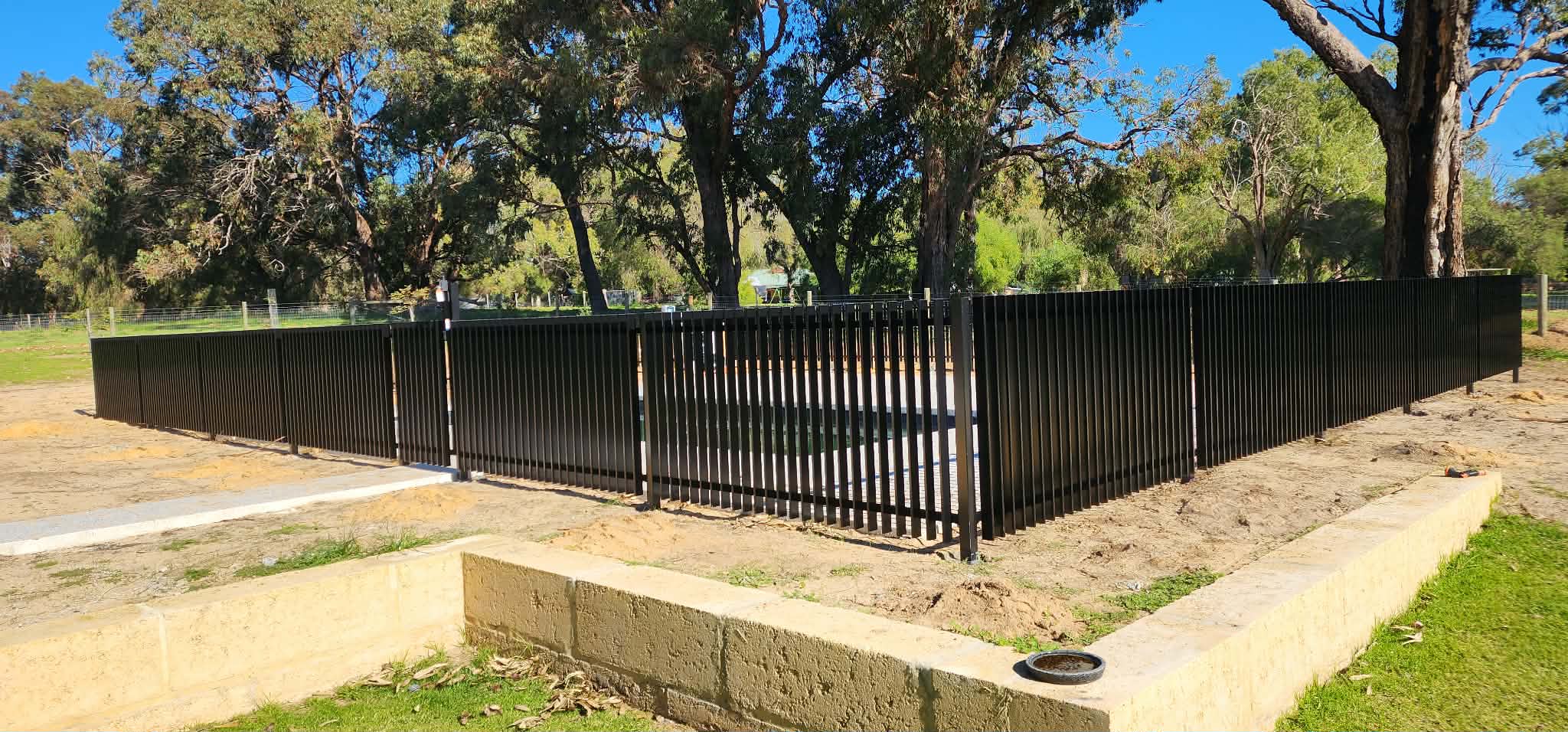 Matte black aluminium perimeter fencing with vertical slat posts surrounding a property