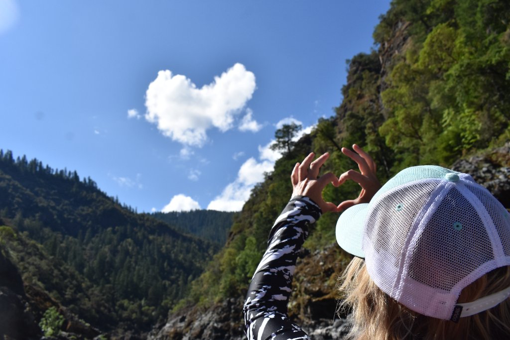 Person making a heart shape with hands against the canyon skyline