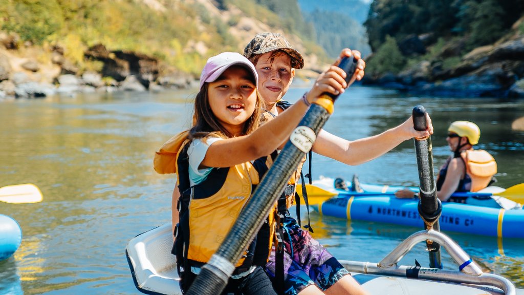 Kids paddling on the Rogue River with mountains in the background