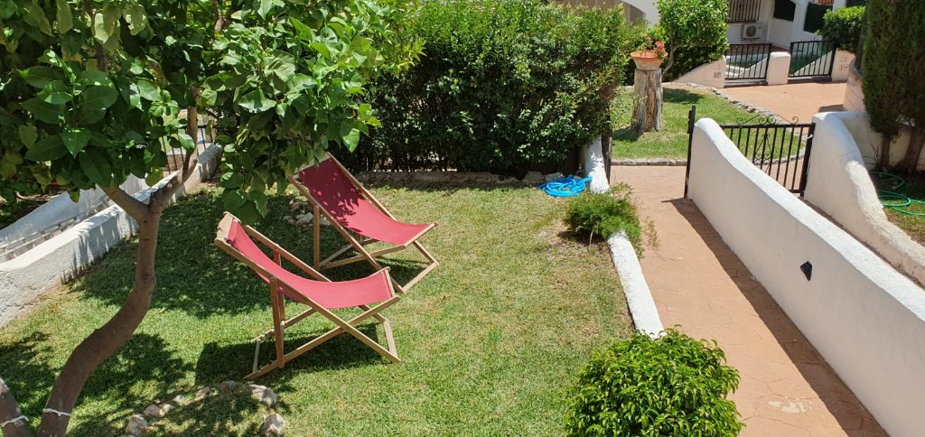 Jardín con tumbonas rojas y césped
