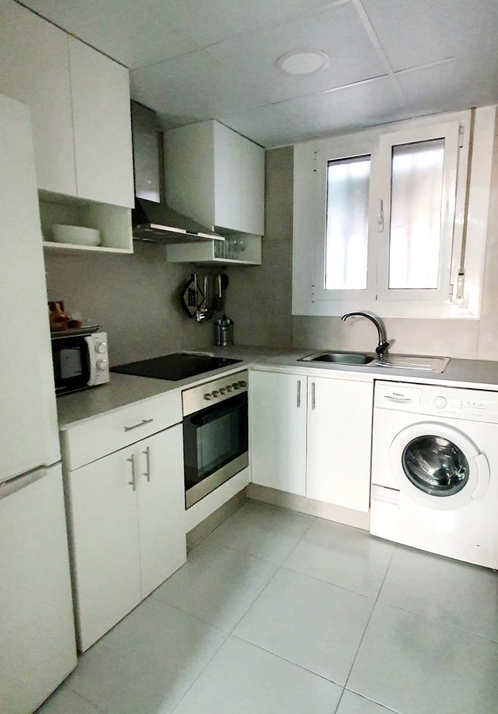 Cocina con lavadora y ventana