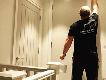 A Haime & Son painter cutting in around a door casing on a landing