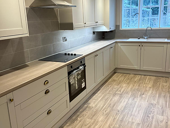 Galley kitchen after: cream cabinetry, wood-effect worktops and grey splashback