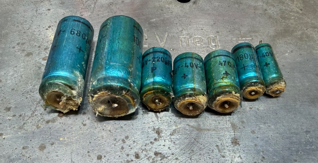 Seven corroded and leaking electrolytic capacitors removed from the 1969 Jaguar radio during vintage car radio repair