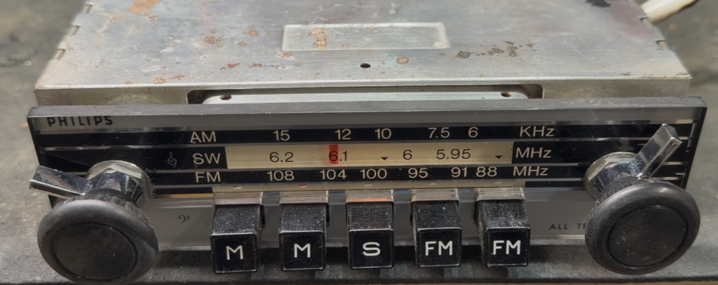 Vintage Philips car radio chassis removed from a 1969 Jaguar, showing AM/SW/FM tuning dial and push-button controls