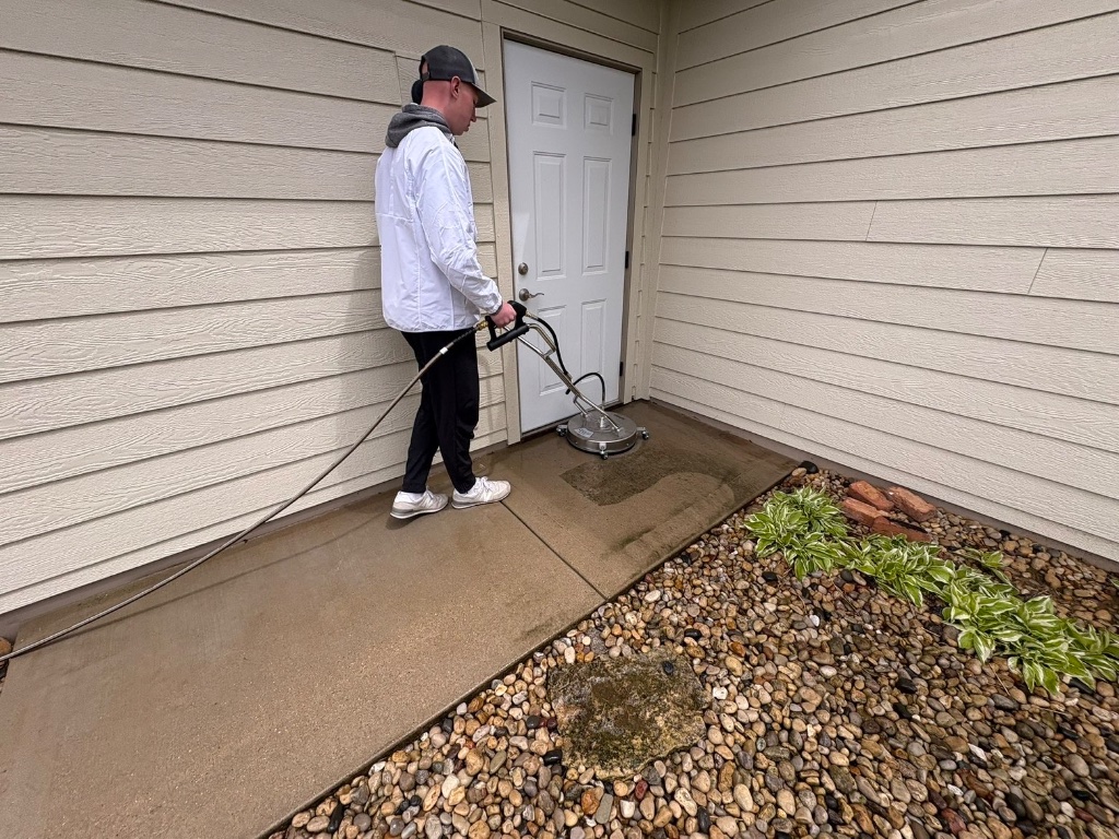 Technician pressure washing a home entryway walkway
