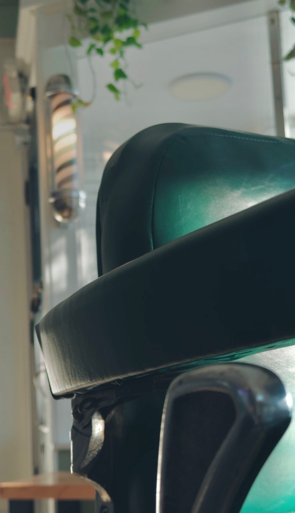 Close-up of vintage barber chair headrest in deep green leather