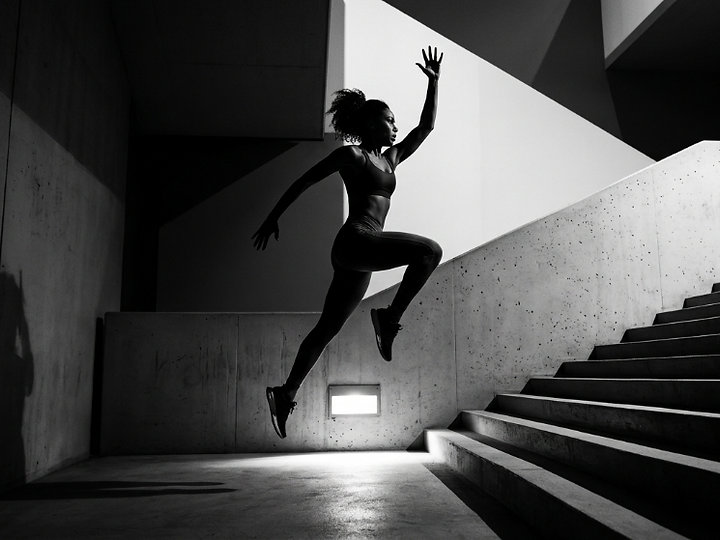 Athlete mid-leap in a concrete stairwell