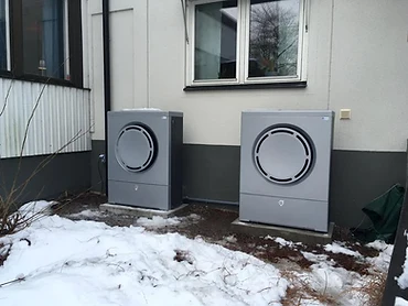 Två utomhusenheter till värmepump monterade utanför en fastighet
