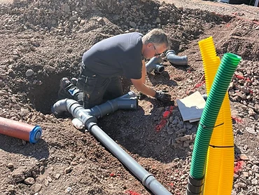 Montör installerar markförlagda avloppsrör vid ett grundarbete