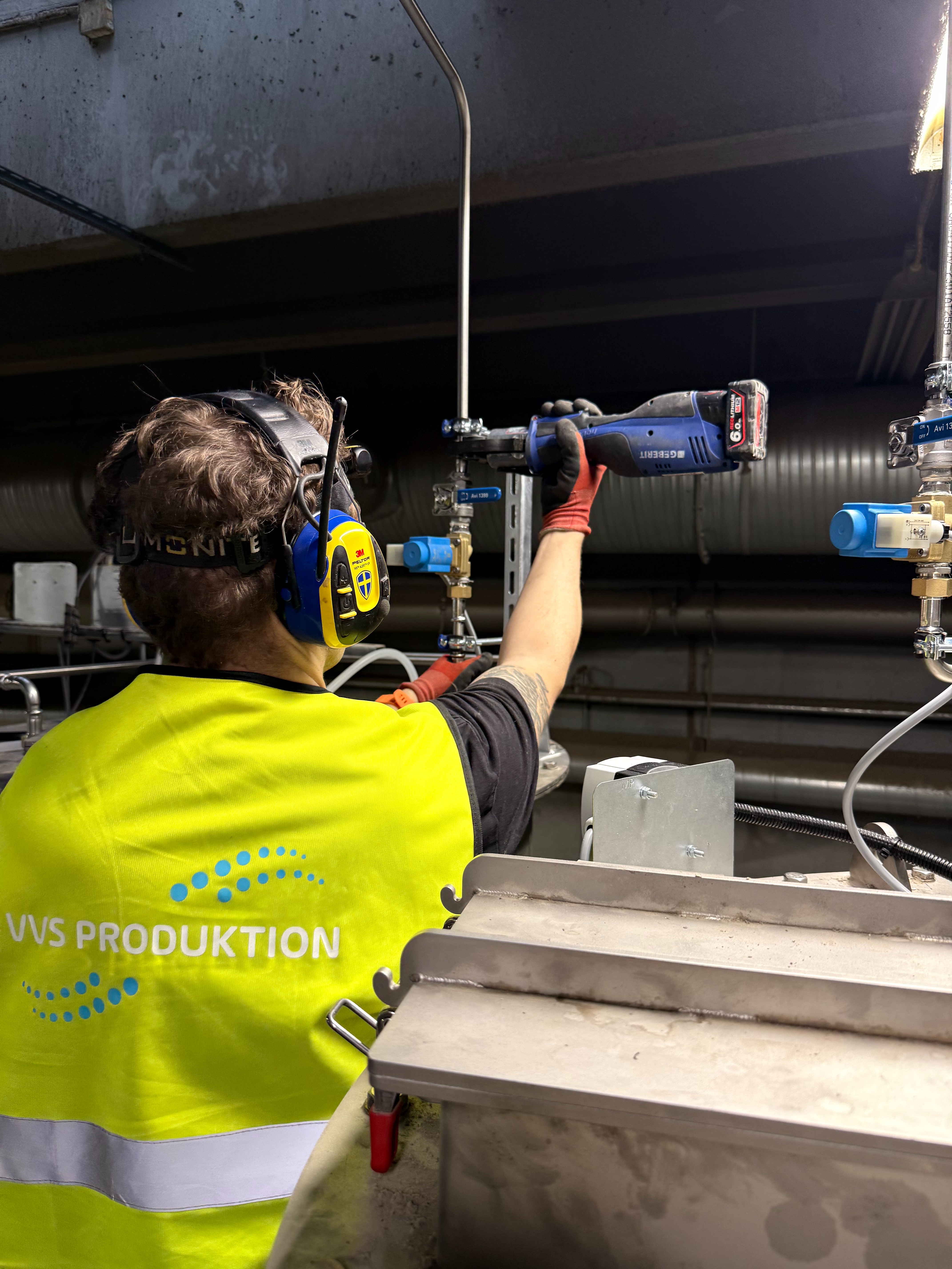Rörmokare utför VVS-arbete i industrimiljö