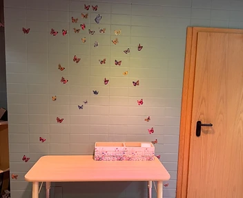 Der gestaltete Raum mit sagegrüner Wand, Holztisch und Schmetterlings-Dekoration