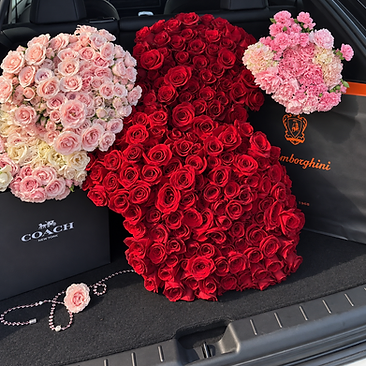 Oversized red heart-shaped rose arrangement with smaller bouquets inside a car trunk