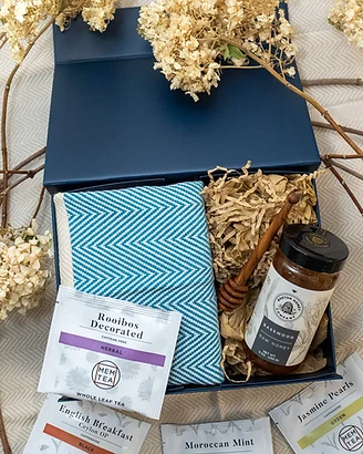 A curated gift box with dried hydrangea accents on a soft herringbone textile