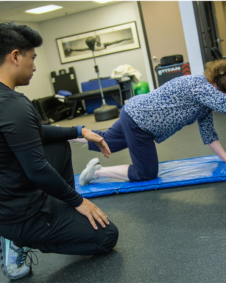 Migma Tamang coaching a client through a controlled bird-dog movement on a training mat.